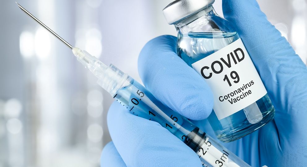 Healthcare cure concept with a hand in blue medical gloves holding Coronavirus, Covid 19 virus, vaccine vial
